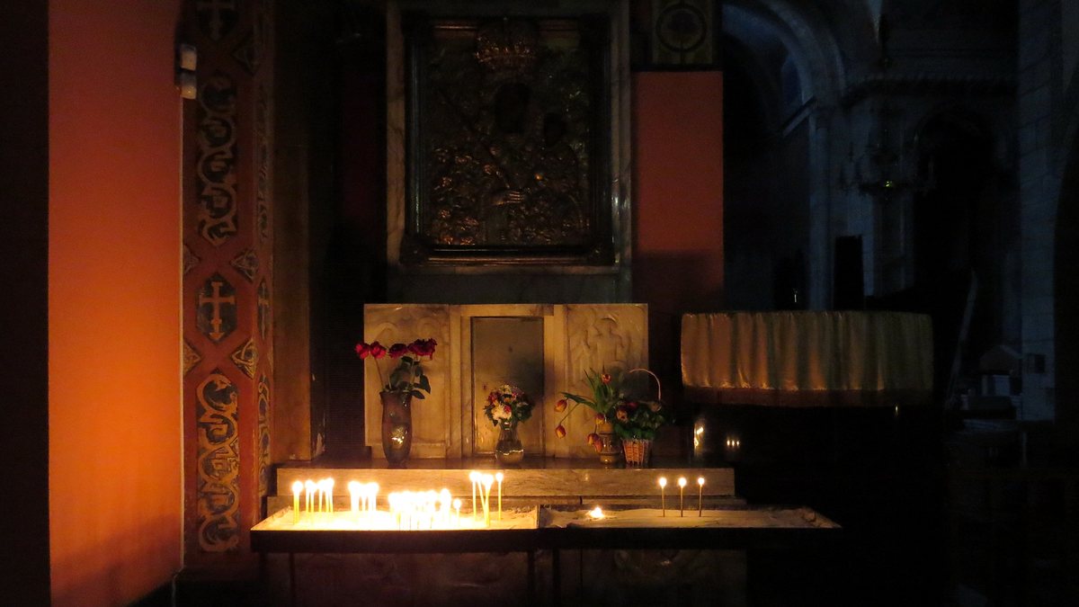 Тонкие восковые свечи горят перед старинной иконой в полутемном храме
